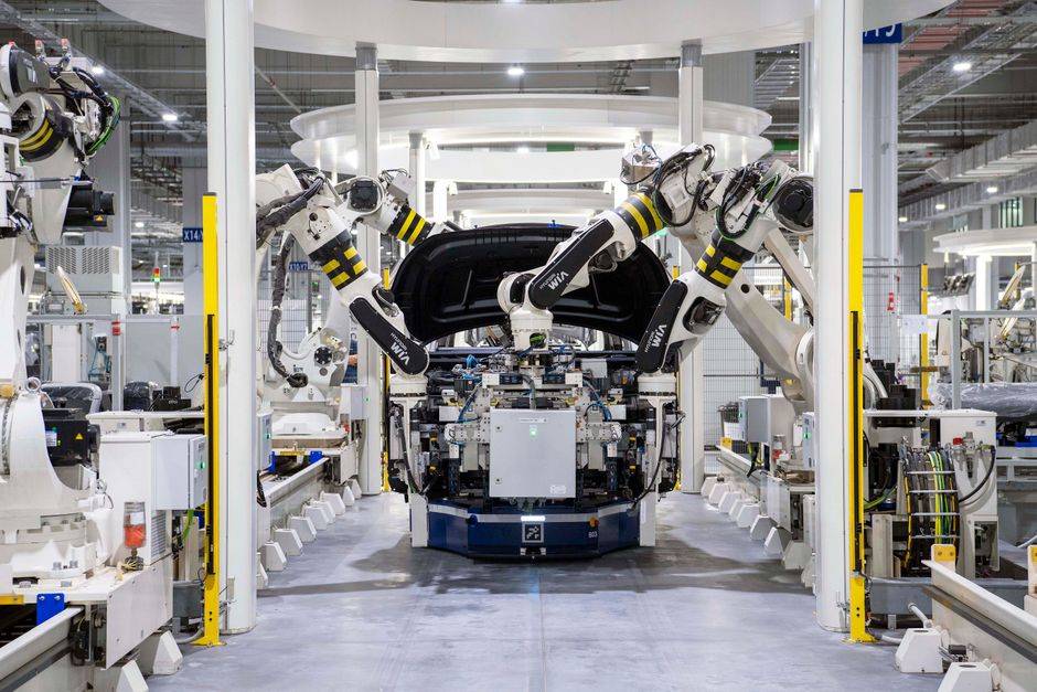 Robots de alta tecnología ensamblando un coche en un entorno de fábrica moderna, mostrando la automatización.
