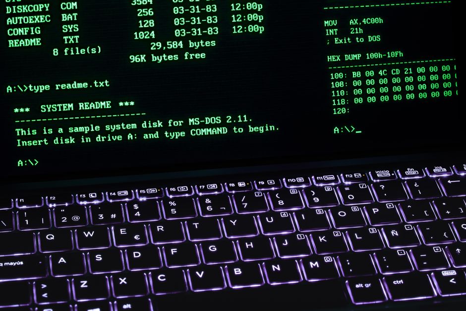 Una pantalla de terminal MS-DOS clásica mostrada en el teclado de una computadora portátil con iluminación brillante.