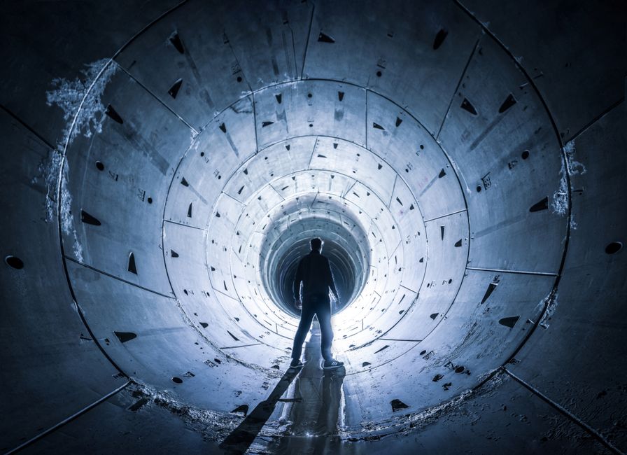 Una silueta misteriosa se encuentra en la entrada iluminada de un túnel de hormigón.