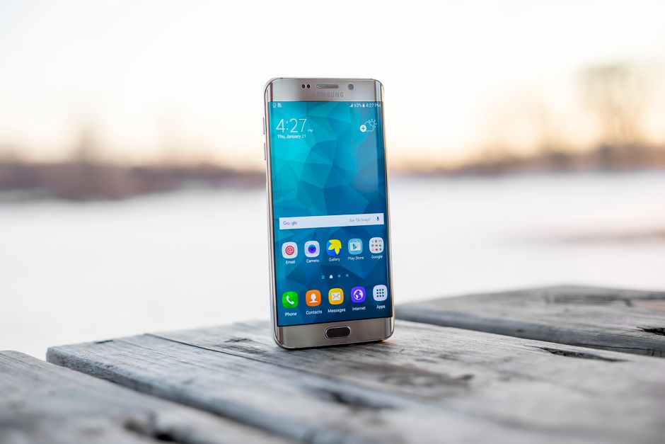 Smartphone Samsung colocado sobre una superficie de madera al aire libre durante el atardecer.