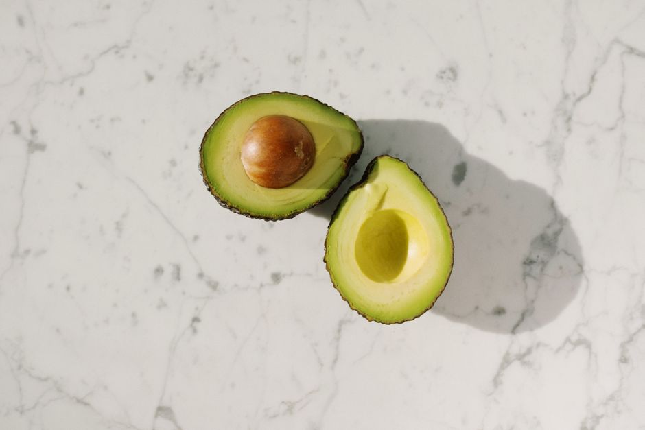 Imagen de alta calidad de mitades de aguacate fresco sobre una superficie de mármol, perfecta para blogs de comida.