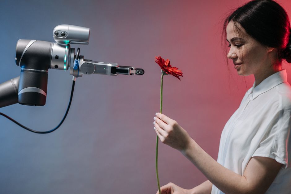 Una mujer recibe una flor roja de un brazo robótico que simboliza la armonía entre la tecnología y la naturaleza.