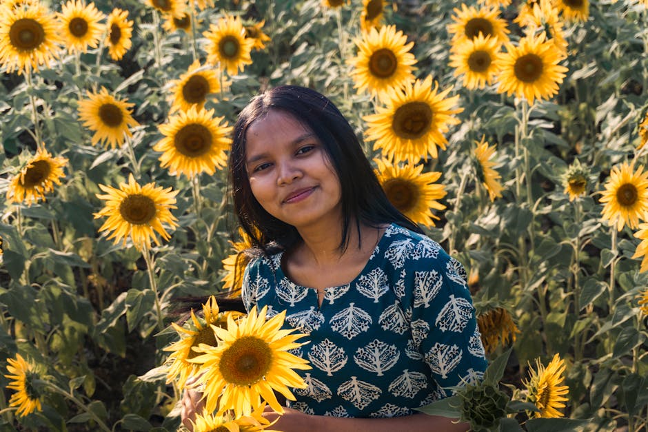 Una joven sonríe en medio de un vibrante campo de girasoles bañado por la luz del día.