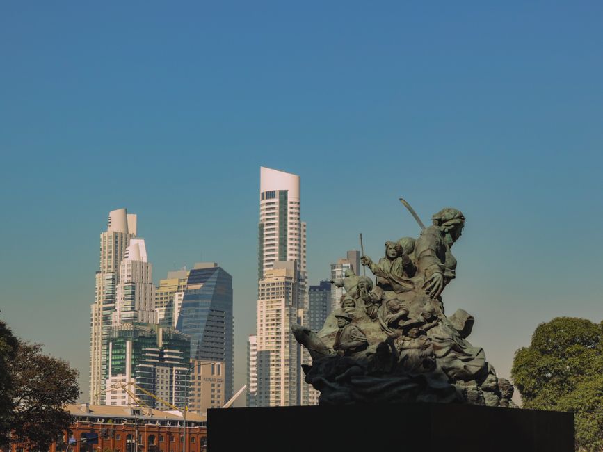 Escultura con rascacielos modernos en Buenos Aires, mostrando la arquitectura urbana.