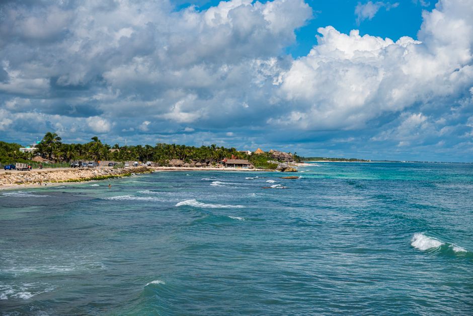 Vista costera vibrante de Tulum con aguas turquesas y vegetación exuberante bajo cielos azules brillantes.