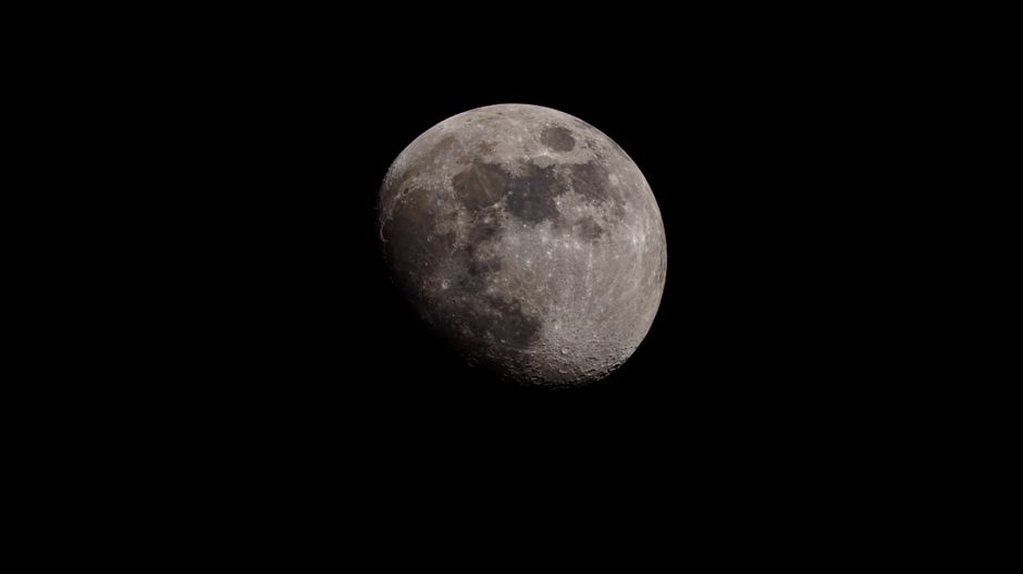 Una fotografía detallada de la media luna contra un cielo oscuro, mostrando sus cráteres y texturas.