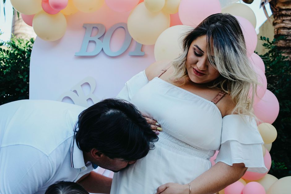 La pareja espera con alegría la llegada de su nuevo bebé durante la celebración de revelación de género con globos y amor.