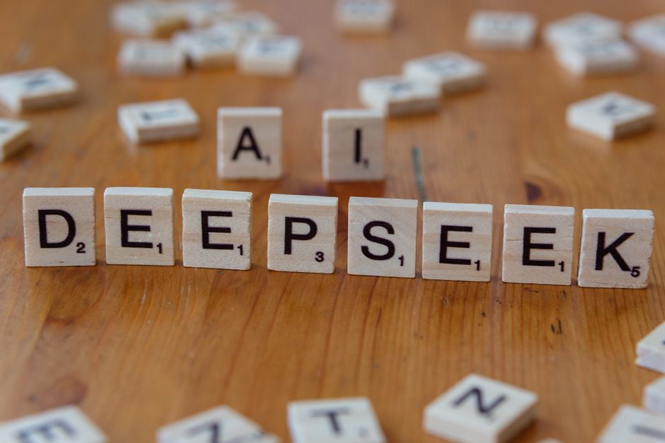Fichas de Scrabble de madera formando 'DEEPSEEK' con 'AI' sobre una mesa de madera, ilustrando conceptos de IA de manera creativa.