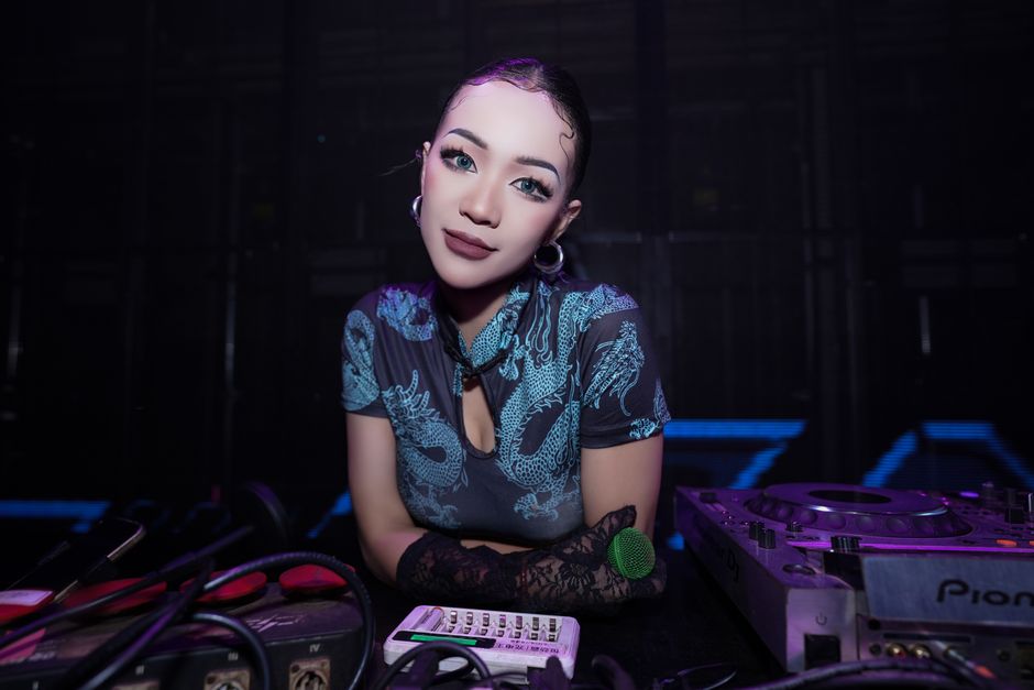 Una DJ vestida con un cheongsam tradicional, actuando en una animada discoteca.