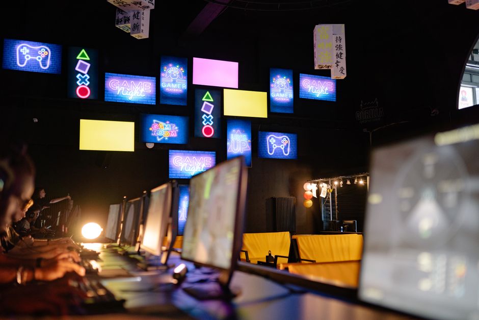 Sala de juegos iluminada con pantallas coloridas y letreros de neón, creando una experiencia de juego inmersiva.