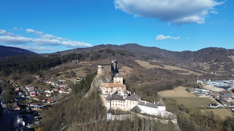 Impresionante vista aérea del castillo de Orava rodeado de colinas y un pequeño pueblo en Eslovaquia.