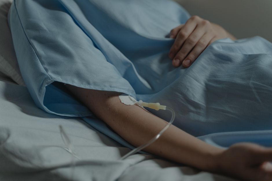 Primer plano de un paciente en una cama de hospital con un goteo intravenoso conectado al brazo.