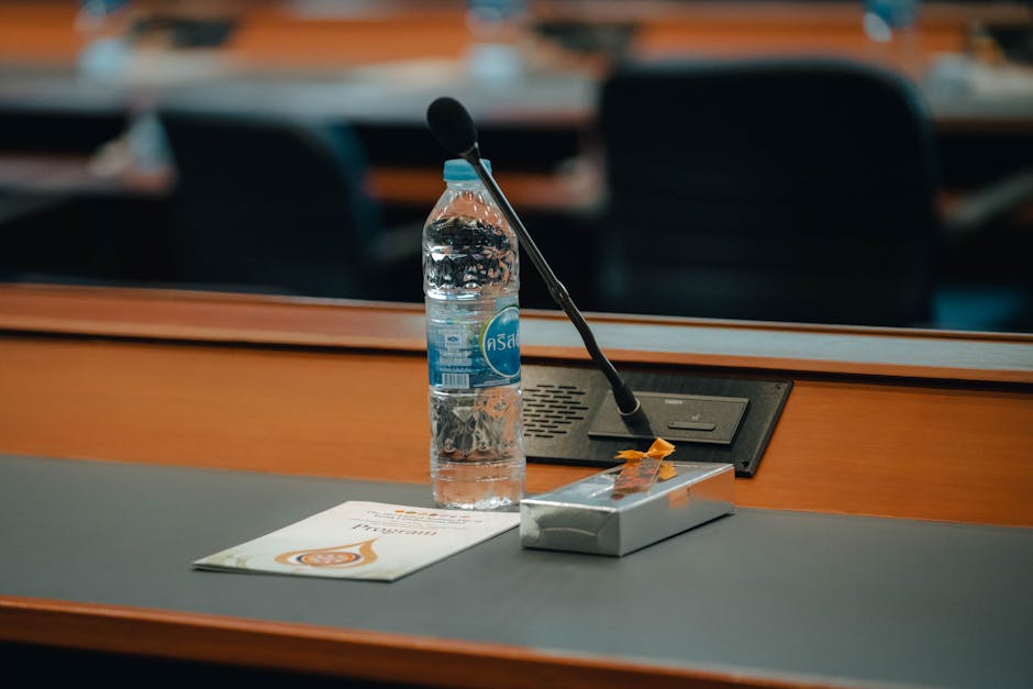 Mesa de conferencias en Tailandia con agua embotellada, micrófono y documentos. Ideal para reuniones de negocios.