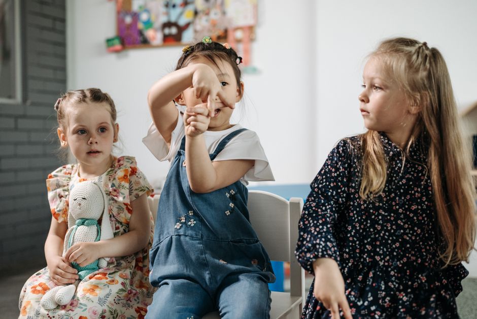 Tres niños diversos sentados y jugando en un aula brillante de jardín de infancia.