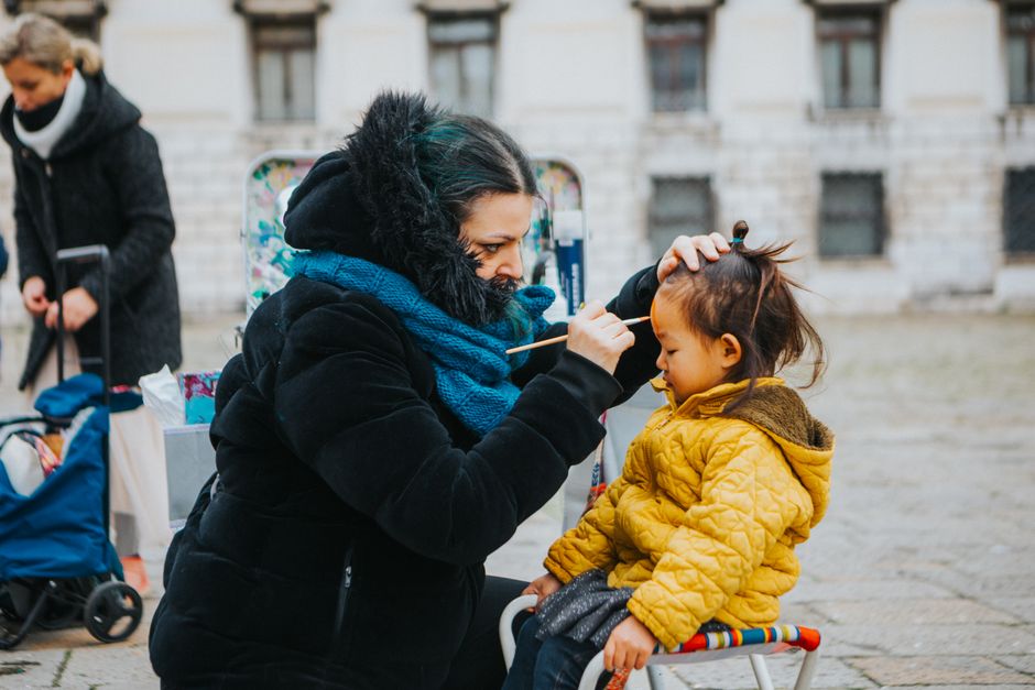 Una mujer pinta la cara de un niño al aire libre durante un frío día de invierno.