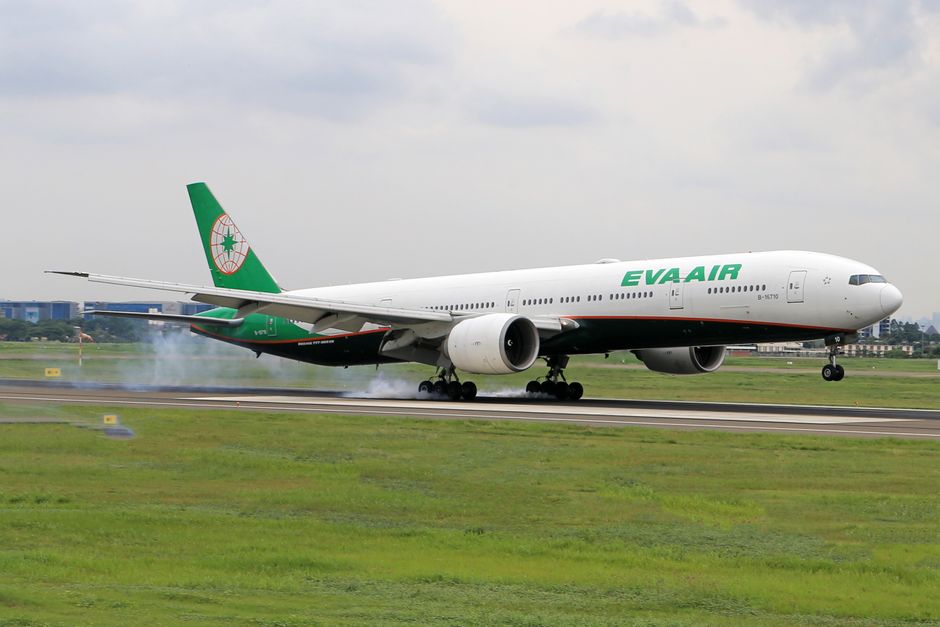Boeing 777 de EVA Air aterrizando con humo de tren de aterrizaje en el aeropuerto.