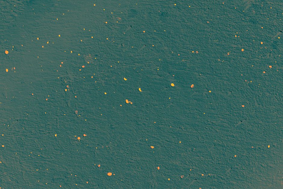 Una textura abstracta vibrante con puntos amarillos y naranjas sobre una superficie verde, ideal para proyectos creativos.