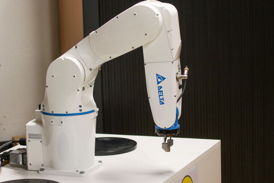 Primer plano de un brazo robótico de la marca Delta en un entorno industrial, mostrando tecnología de automatización.