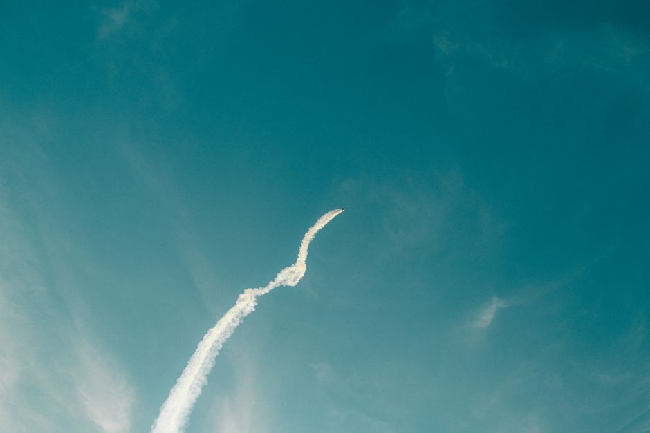 Un avión acrobático deja una estela de humo blanco contra un cielo azul despejado, mostrando patrones de vuelo dinámicos.