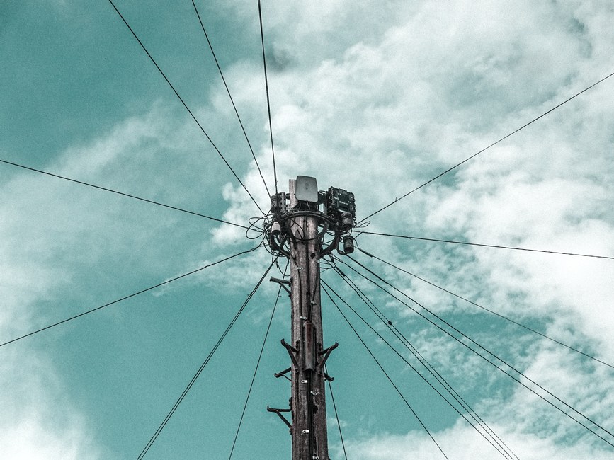Poste de telecomunicaciones con cables contra el cielo azul en Shrewsbury, Inglaterra.