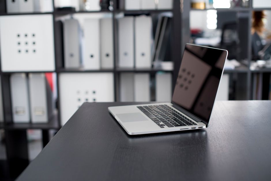 MacBook Pro mostrado en un escritorio minimalista con estantes al fondo.
