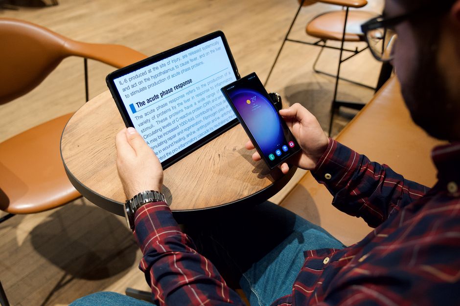 Un hombre usando una tableta y un smartphone en una mesa de café en un entorno moderno.