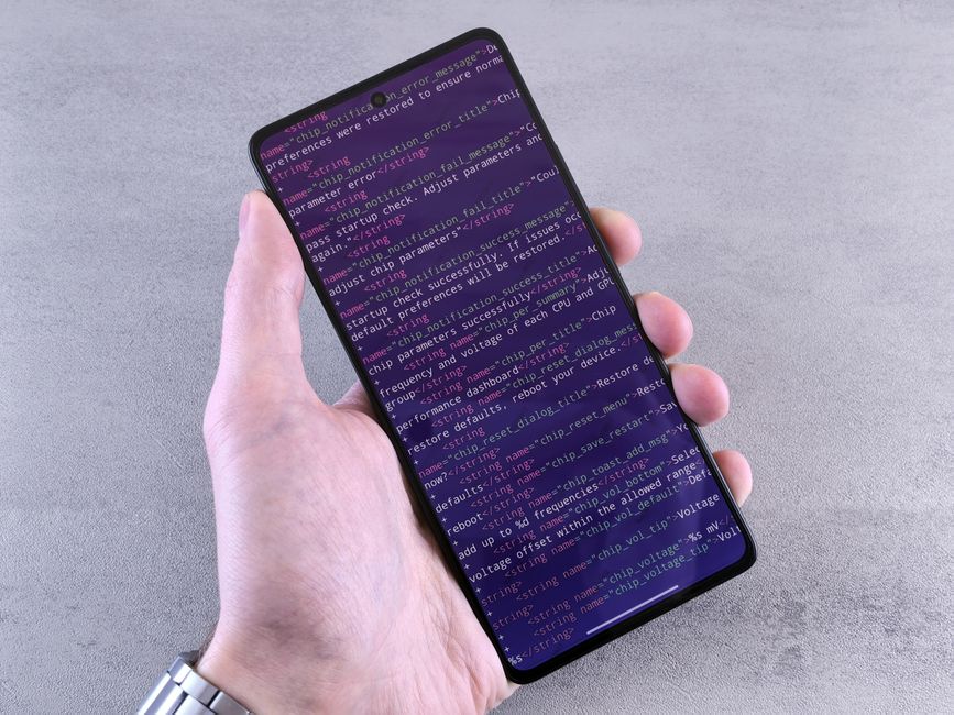 Primer plano de un teléfono inteligente que muestra un texto de código sostenido en la mano de una persona.