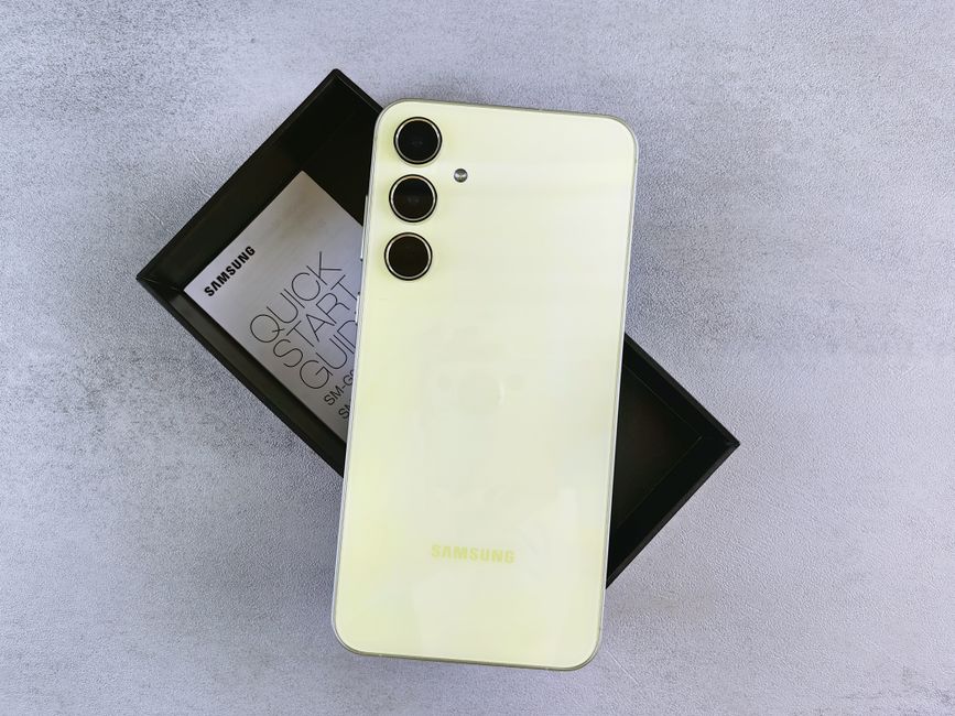 Elegante teléfono inteligente amarillo con diseño de triple cámara y logotipo en un elegante empaque.
