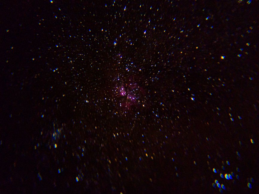 Una vista fascinante de un cielo lleno de estrellas con una distintiva nebulosa rosa en el espacio profundo.