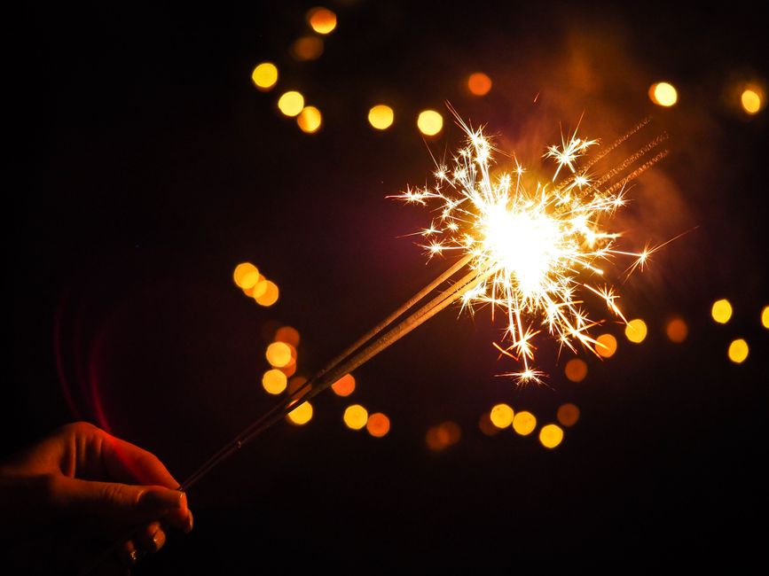 Una vibrante chispa brillando contra un fondo oscuro con luces bokeh, simbolizando la celebración.