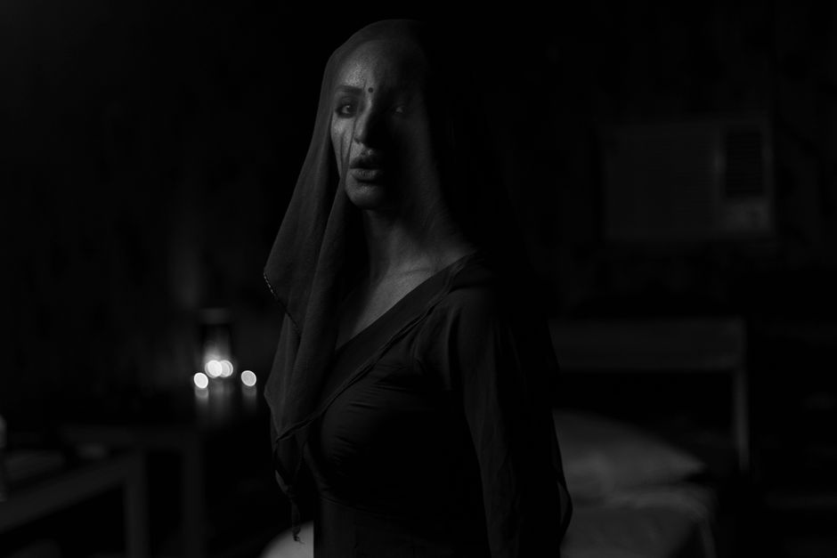 Retrato en blanco y negro de una mujer velada con ropa oscura, que irradia un ambiente misterioso.