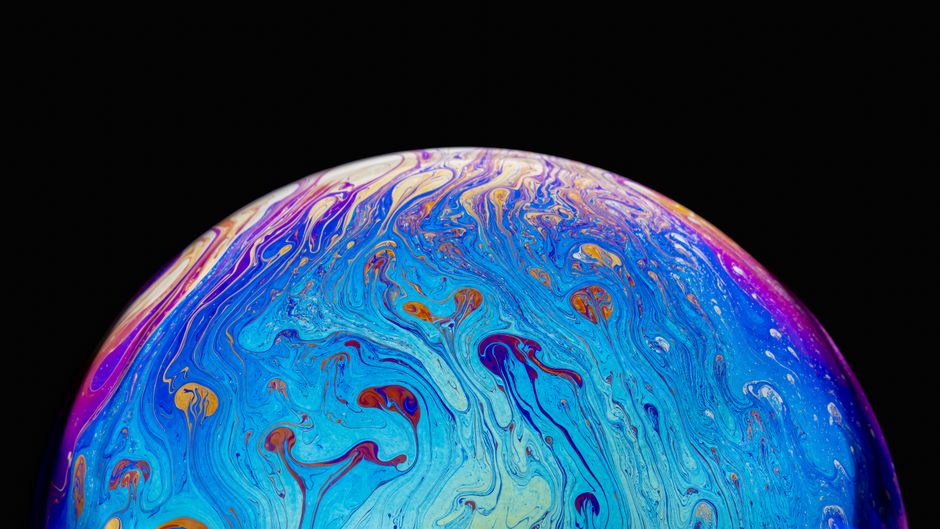 Esfera abstracta colorida con patrones giratorios sobre fondo negro que resaltan texturas iridiscentes.