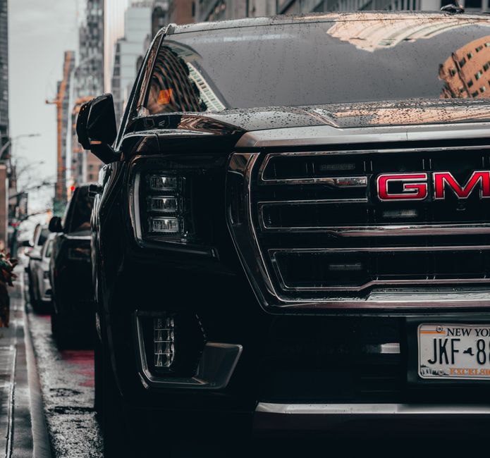 Vehículo GMC negro aparcado en las calles lluviosas de Nueva York, mostrando el estilo de vida urbano.