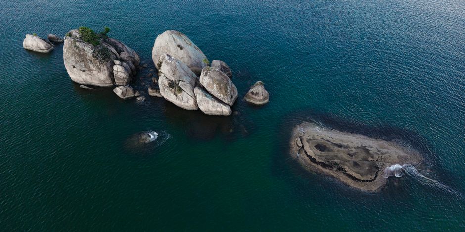 Impresionante imagen aérea de rocas rugosas a lo largo de la costa en Vitória, mostrando la belleza natural del mar.