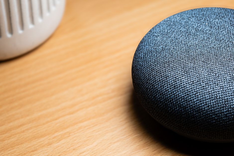 Una vista de cerca de un altavoz inteligente sobre una mesa de madera, capturando detalles de textura.