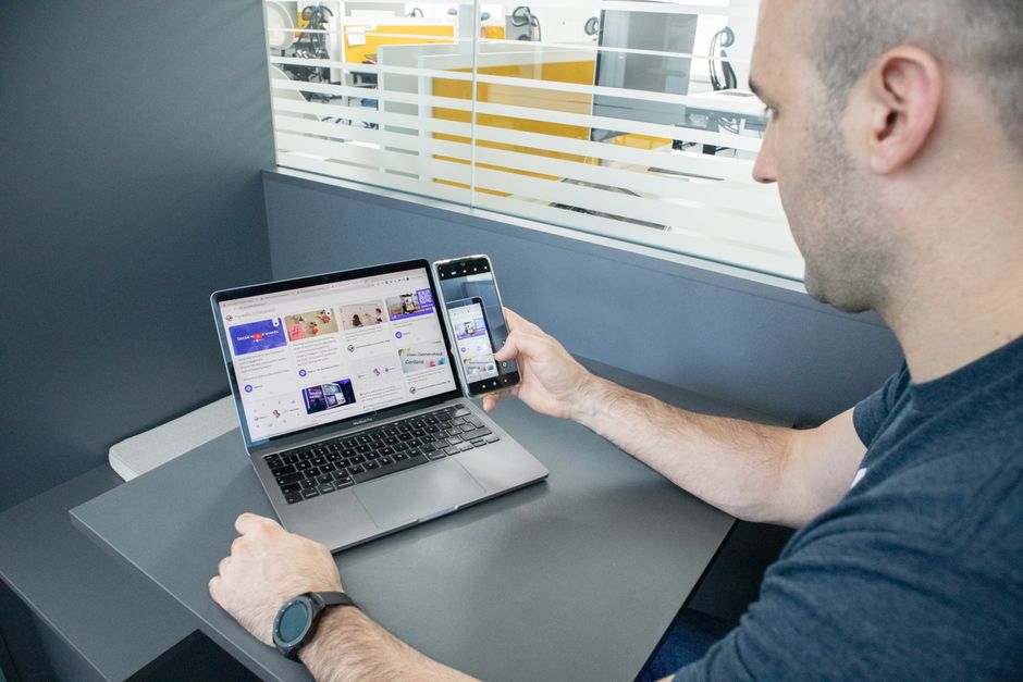 Un hombre multitarea con un laptop y un smartphone en un espacio de oficina contemporáneo, mostrando el uso de la tecnología.