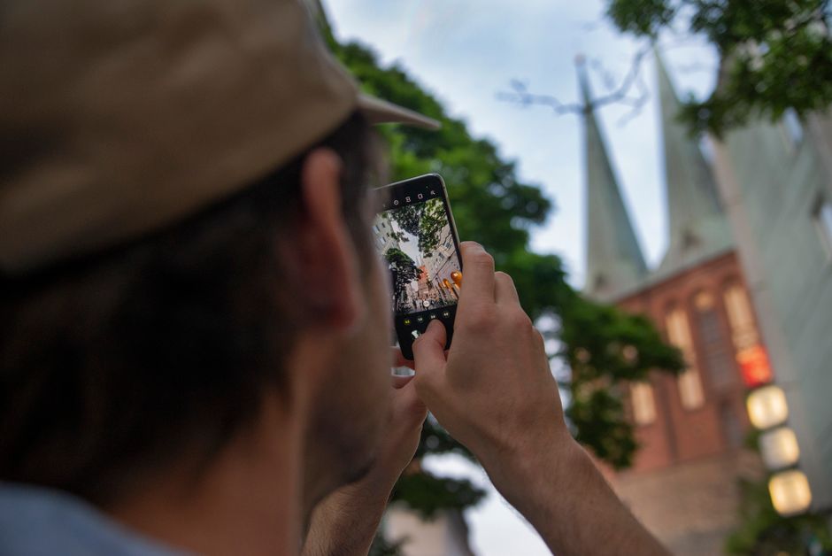 Una persona captura las icónicas torres de iglesias de Berlín con un smartphone, al aire libre.