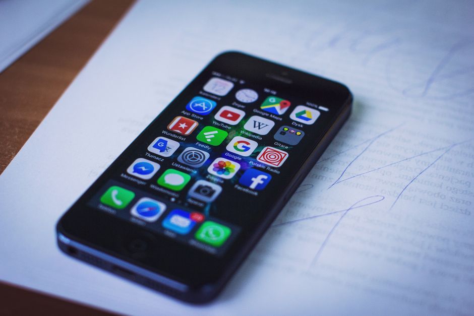 Smartphone moderno mostrando varias aplicaciones reposando sobre documentos en interiores.