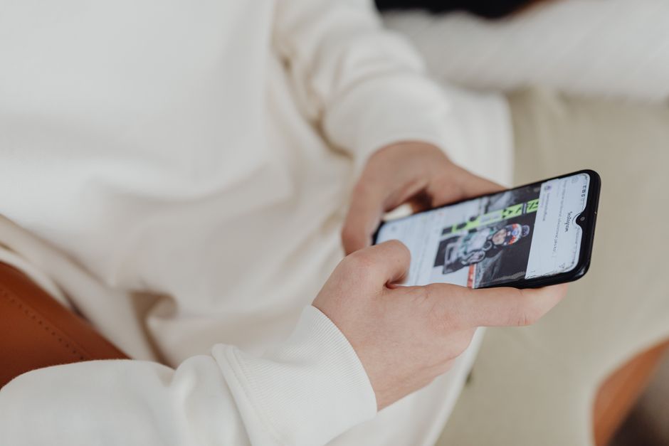 Una vista cercana de manos sosteniendo un smartphone que muestra una imagen deportiva en interiores.