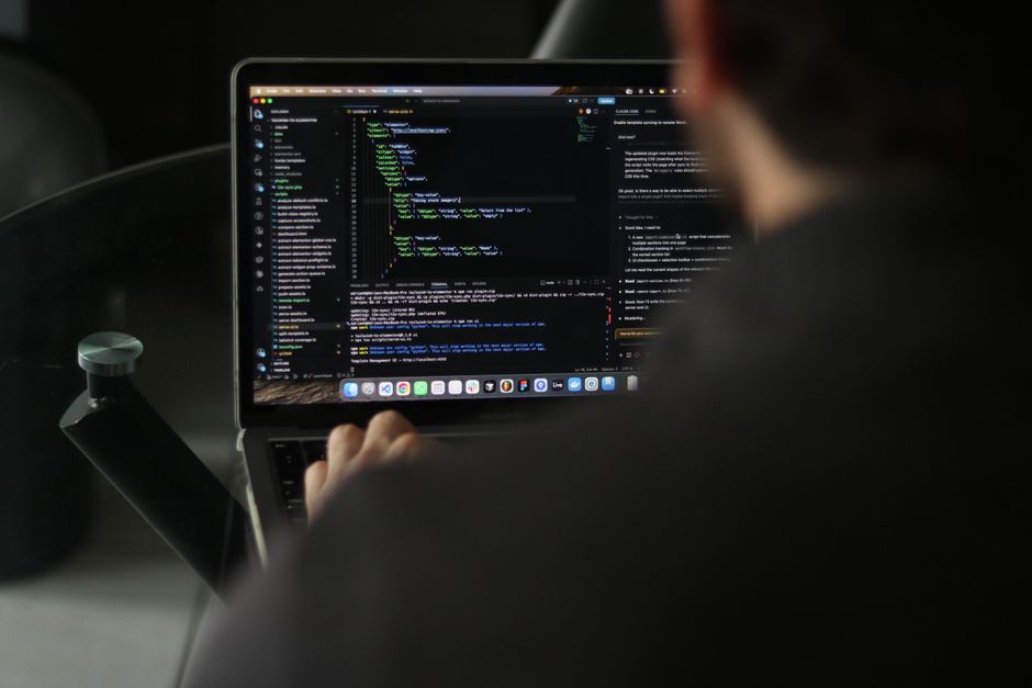 Un desarrollador enfocado escribiendo código en un portátil en un espacio de trabajo interior.