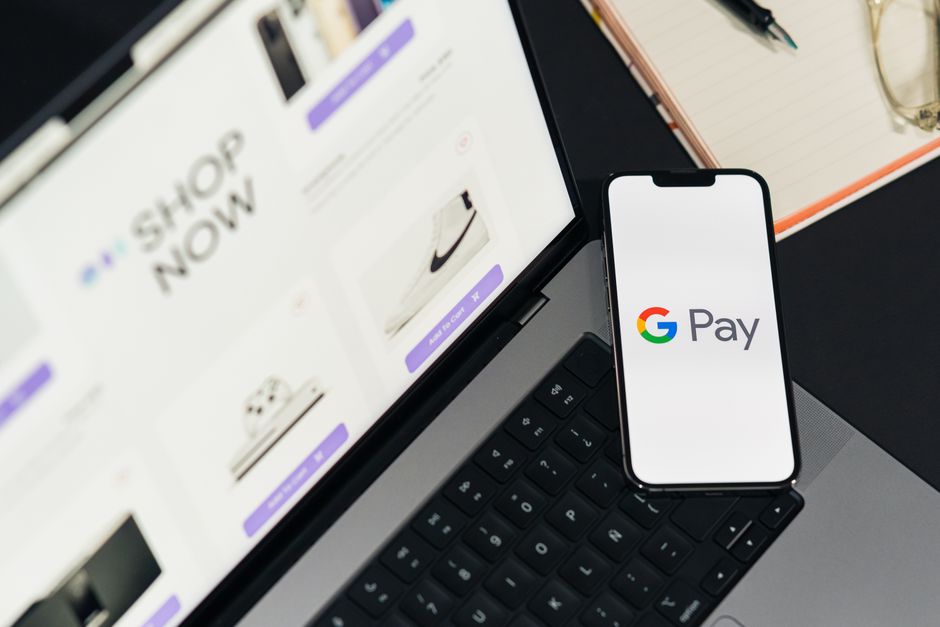 Teléfono inteligente con Google Pay en una computadora portátil para mayor comodidad al realizar compras en línea.