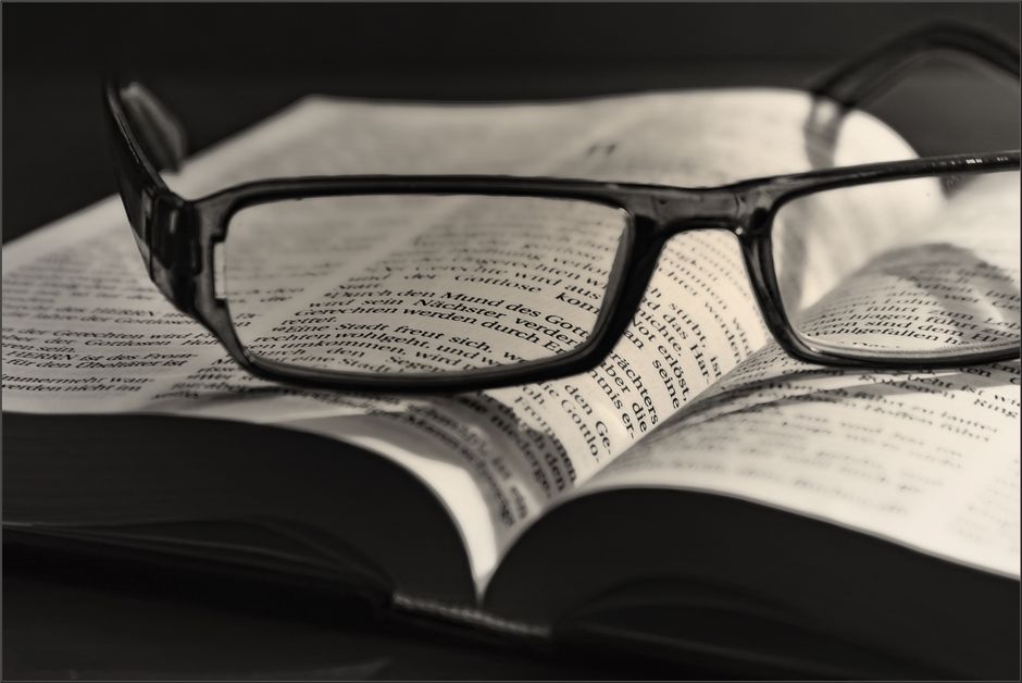 Imagen artística en blanco y negro de gafas descansando sobre un libro abierto. Ideal para conceptos de literatura o visión.