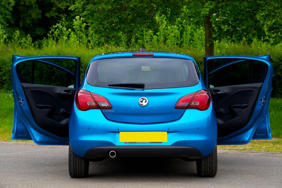 Vista trasera de un Vauxhall Corsa azul con las puertas abiertas en una calle.