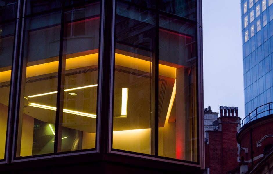 Edificio moderno de oficinas con paneles de vidrio brillando al anochecer, mostrando la arquitectura urbana en Londres.