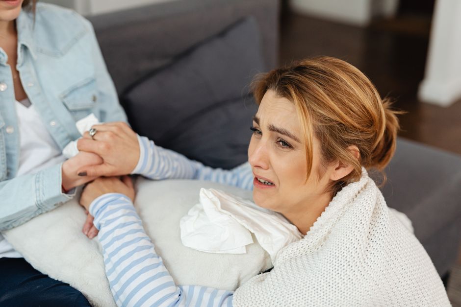 Una mujer llorando es consolada por una amiga, mostrando apoyo emocional y empatía.