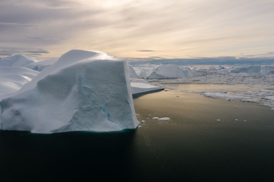 Impresionante vista de grandes icebergs en las tranquilas aguas árticas durante un vibrante atardecer.