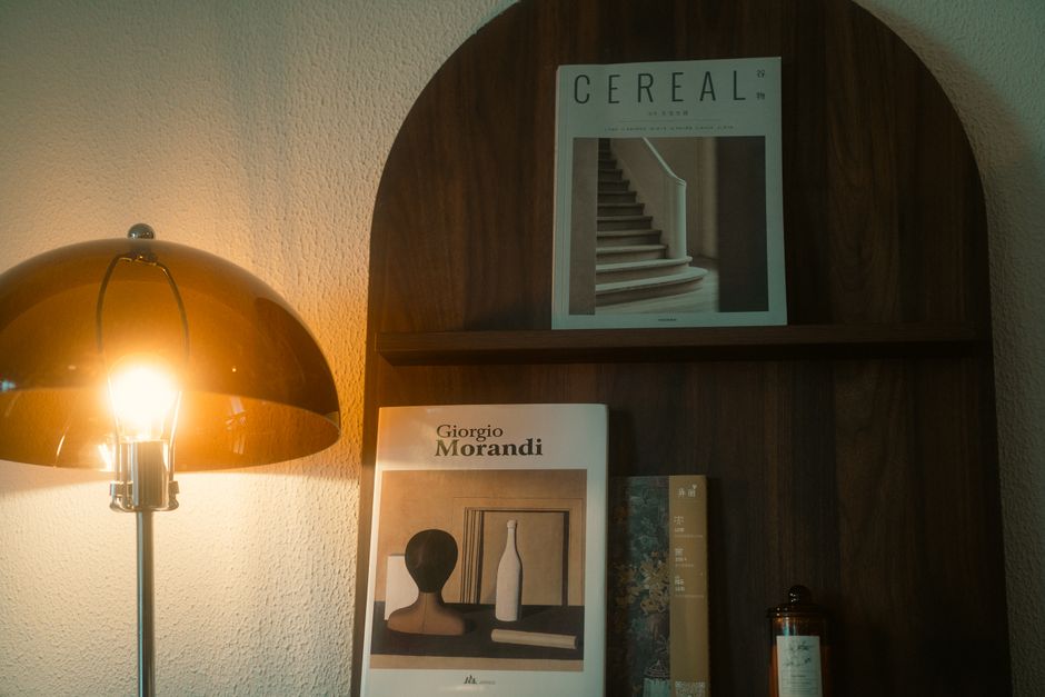 Una elegante configuración con una lámpara moderna y libros de arte en una estantería de madera, perfecta para inspiración en diseño de interiores.