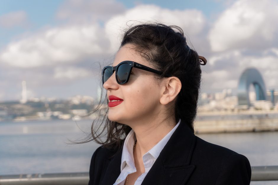 Mujer con gafas de sol disfrutando de las vistas desde el paseo marítimo de Bakú, con el horizonte de Azerbaiyán al fondo.