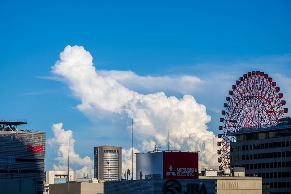 Vibrante horizonte urbano con imponentes edificios y una noria bajo una sorprendente formación de nubes.
