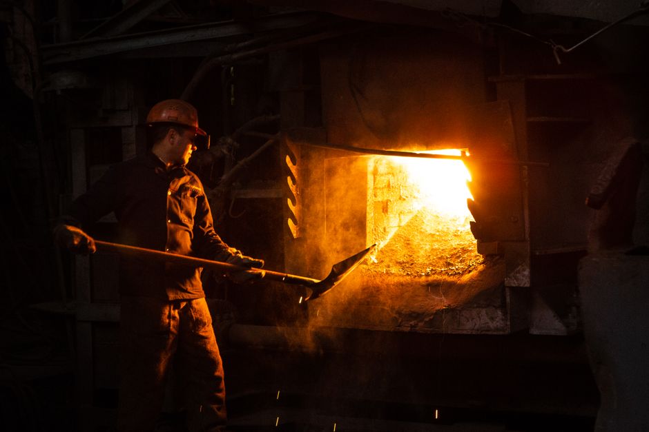 Trabajador manual gestionando un horno en un entorno industrial.